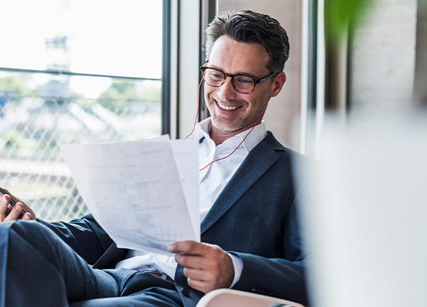 Man smiling while reading paper.