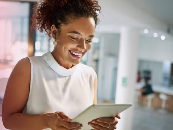 Woman looking at tablet smiling demonstrating the Corporate Traveller SME Corporate Travel Toolkit.