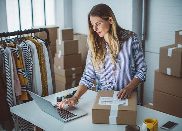 woman holding package and working on laptop