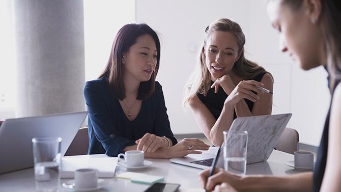 Female professionals reviewing cost management features on a laptop in the office, exploring corporate travel technology solutions