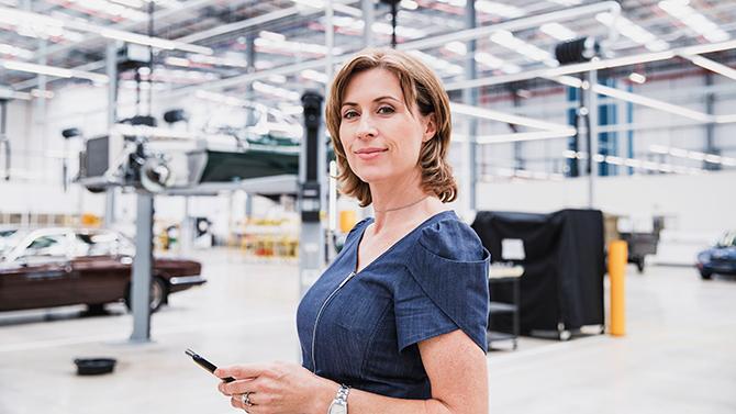 CoT-HW-Female worker in factory with cars and machinery in background