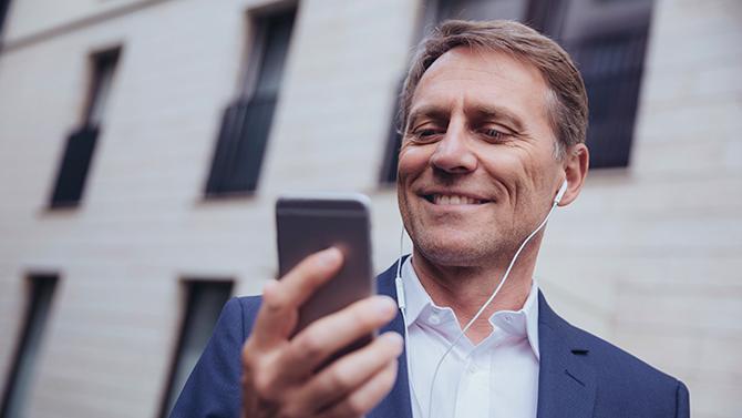 Male professional looking at phone, using corporate travel management technology mobile app for seamless travel planning