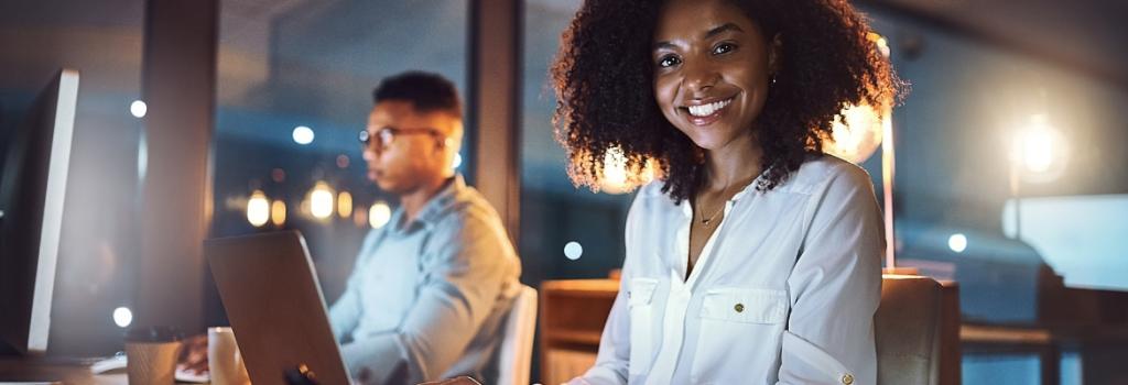 Woman on laptop in office smiling.