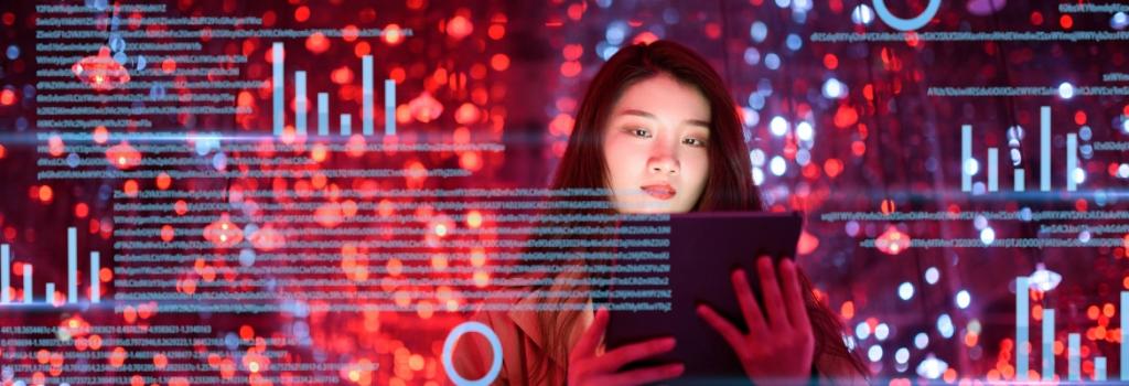 Woman standing in front of tech screen with graphs