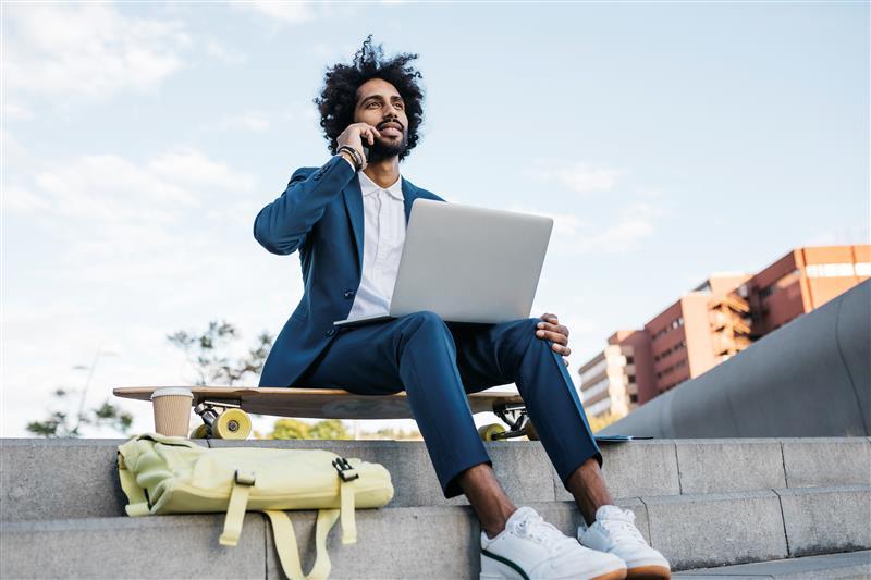 man talking on the phone with a laptop sitting on stairs