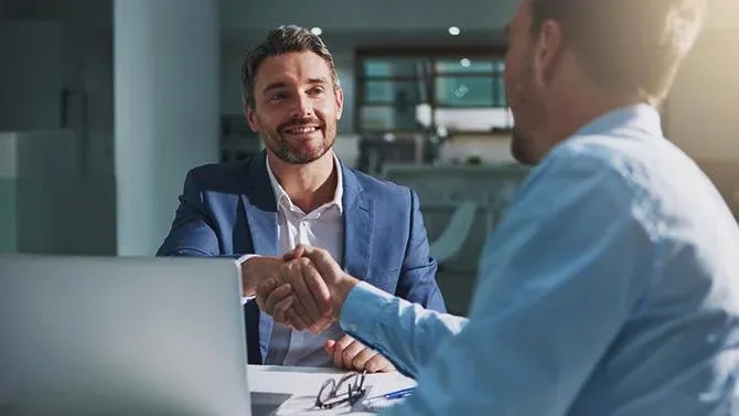 Two men shaking hands over a table celebrating a successful corporate travel partnership