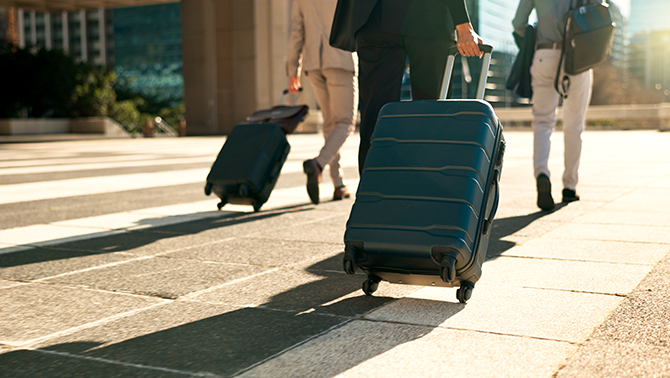 Travellers pulling suitcases outside the airport, preparing for a business travel journey